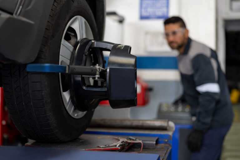Mechanic aligning a car tire at an auto repair shop.