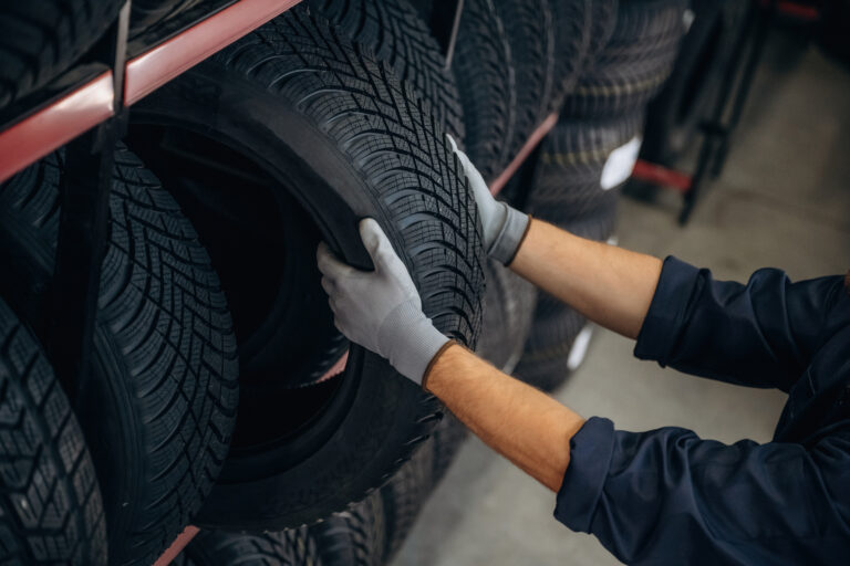 Close up view, taking the tire. Man worker is maintenance station with wheels