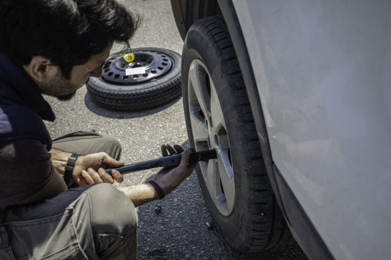 Man Changing Flat Tire with Lug Wrench During Roadside Breakdown.